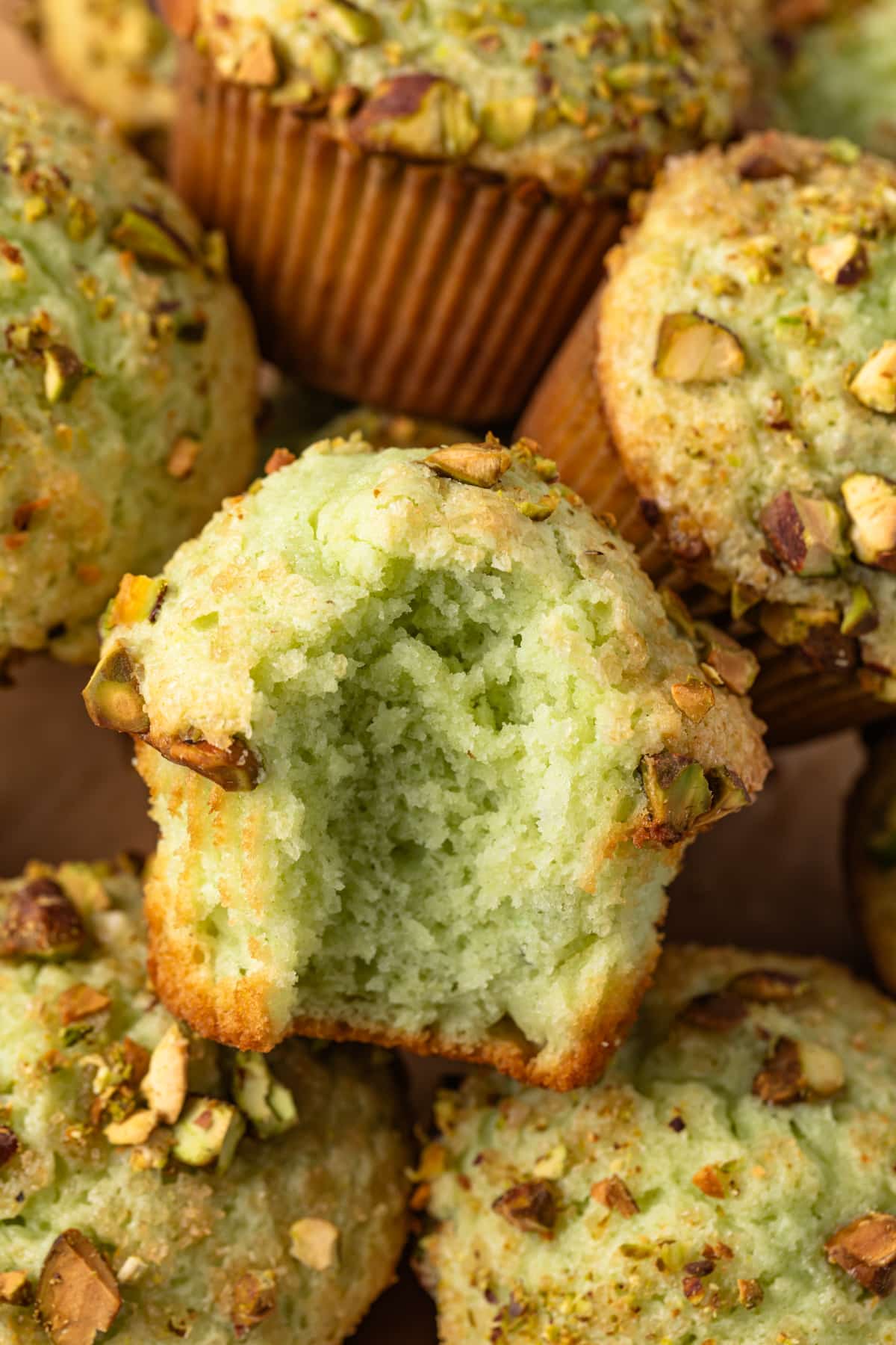 A bite take out of a pistachio muffin.