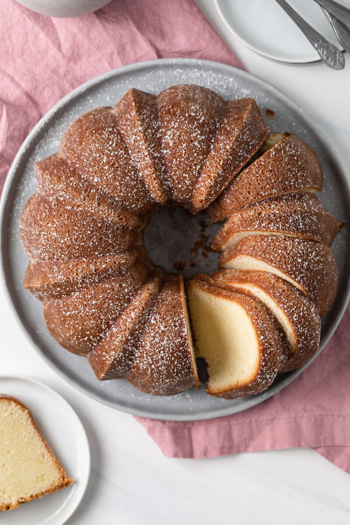 overhead of sliced pound cake on grey plate with pink napkin