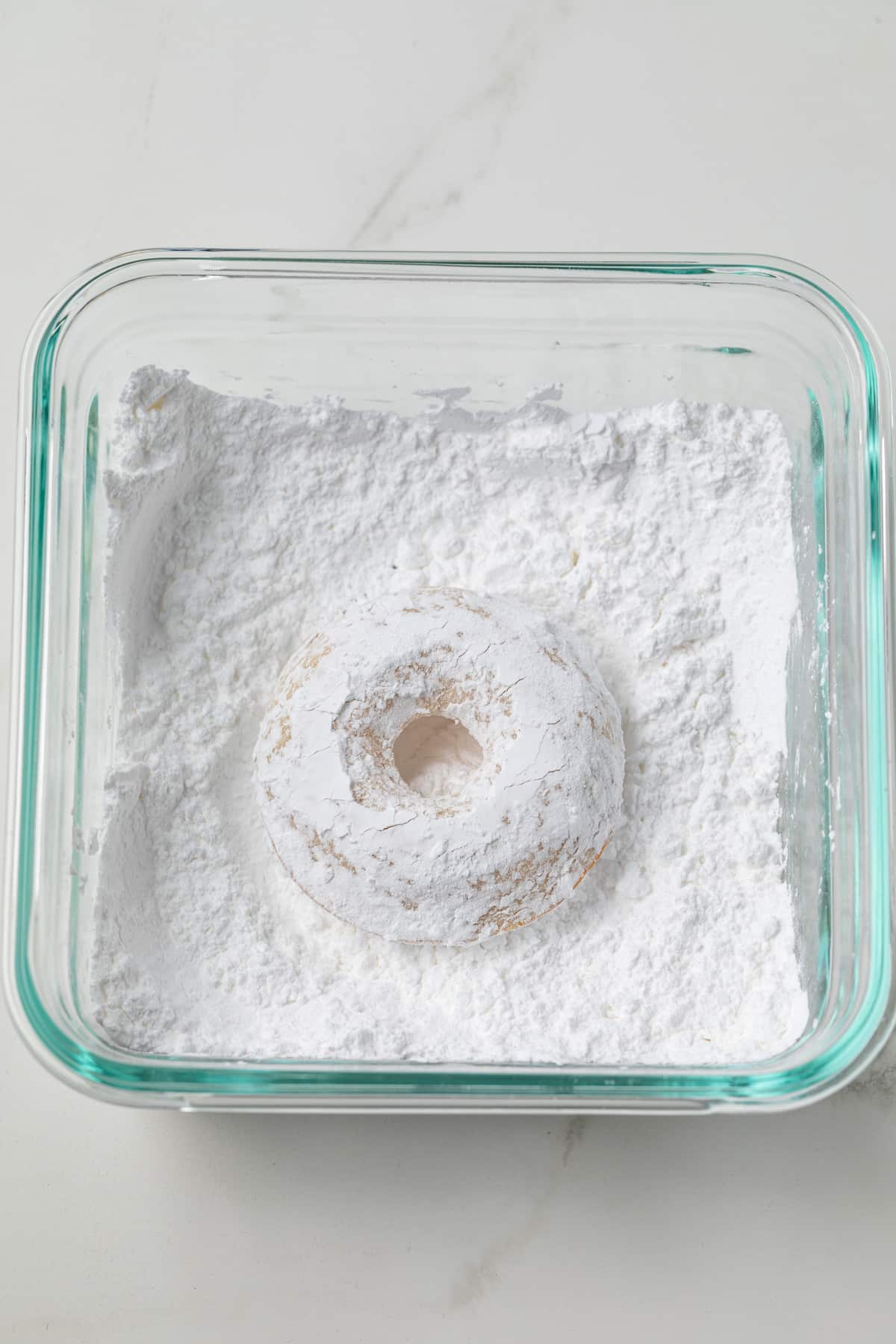 Baked donut coated in powdered sugar.