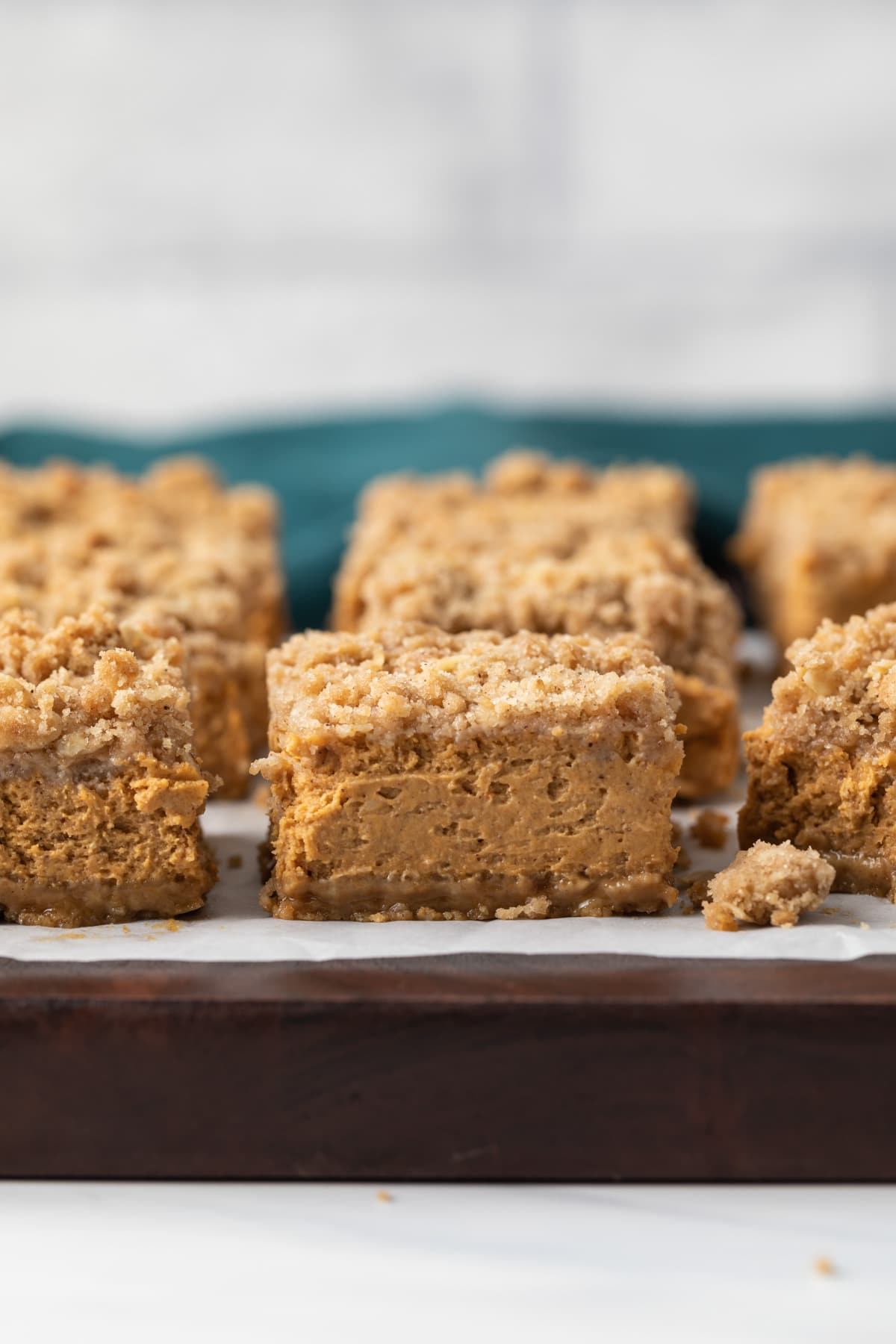 pumpkin bars on brown board with parchment paper
