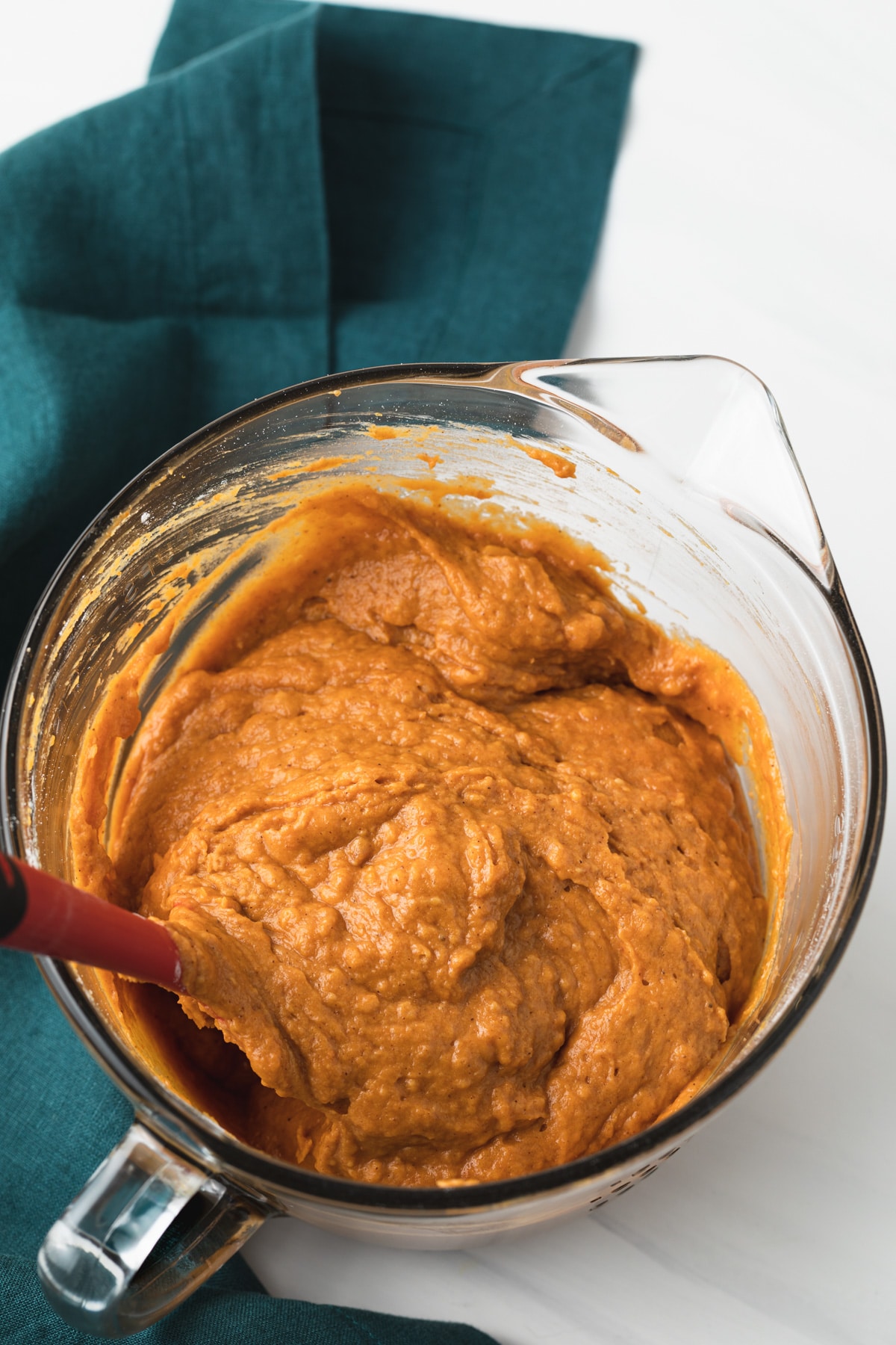 batter for pumpkin bread in glass bowl next to blue-green napkin