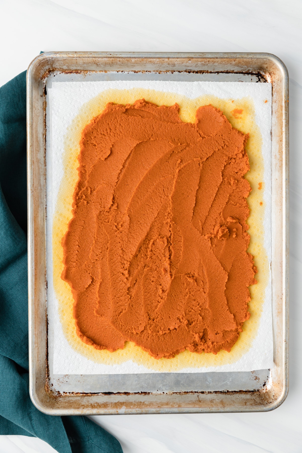 pumpkin puree spread over paper towels on baking sheet