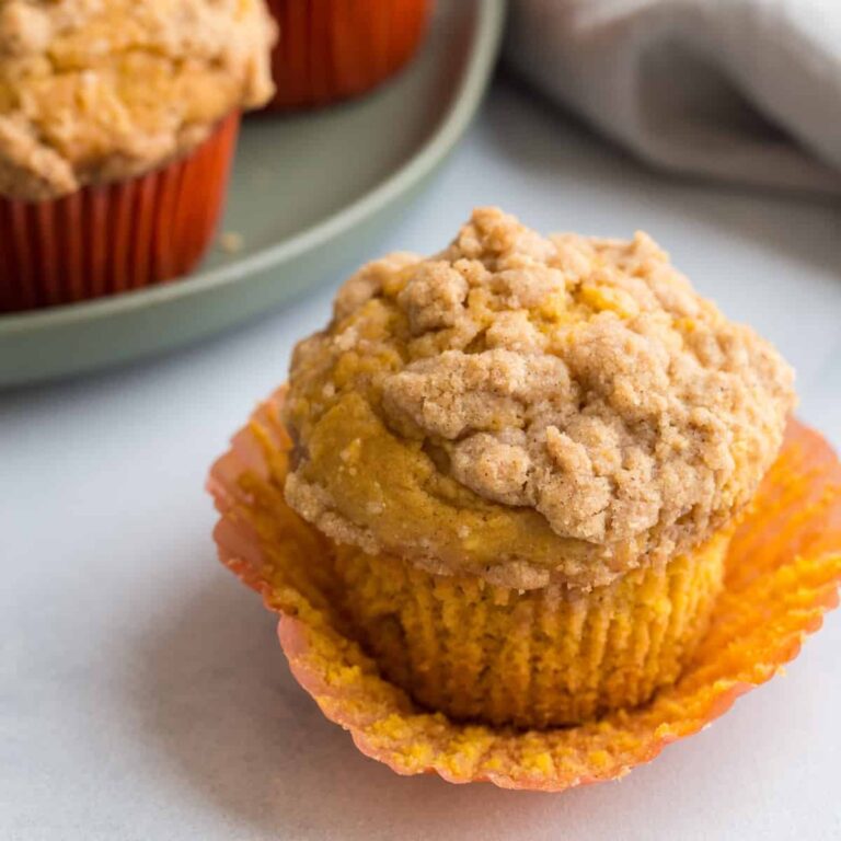 high angled view of a pumpkin muffin with the paper liner being torn away