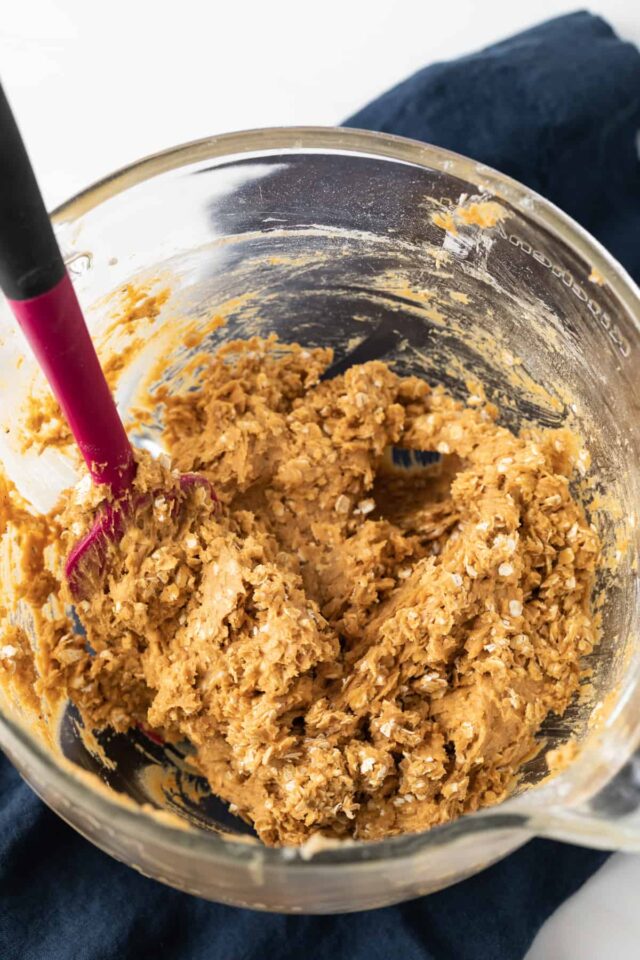 Pumpkin oatmeal cookie dough in glass bowl with pink spatula
