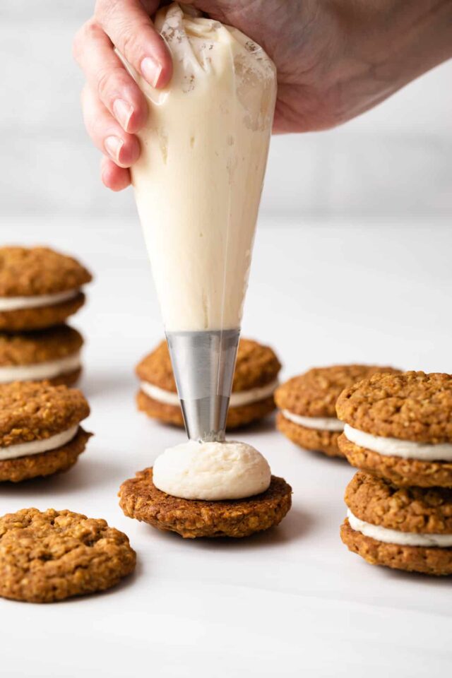 Caramel creme being piped onto pumpkin cookies
