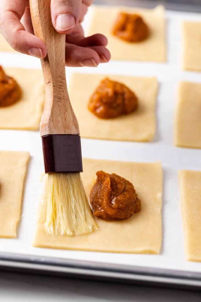 Egg wash being spread on the edges of pastry crust