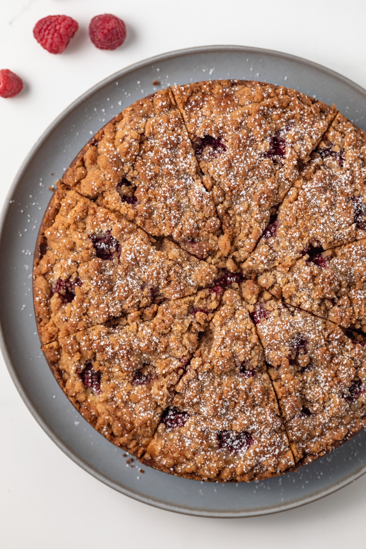 Overhead of sliced raspberry coffee cake on a serving platter.