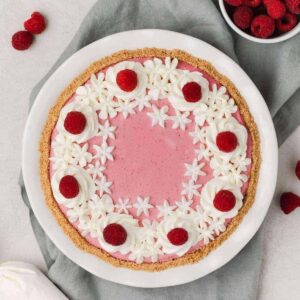 overhead of raspberry pie with whipped cream and fresh raspberries