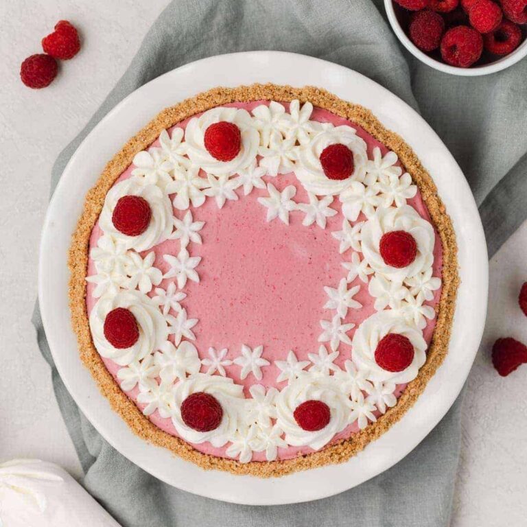 overhead of raspberry pie with whipped cream and fresh raspberries