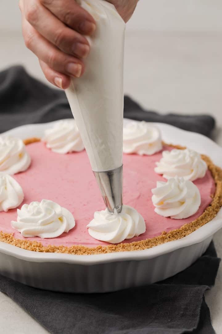 swirls of whipped cream piped on a raspberry pie