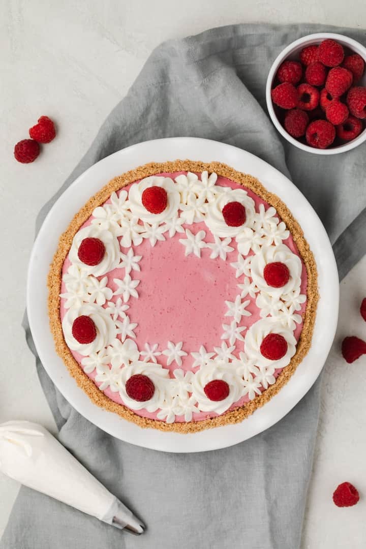overhead of raspberry pie with whipped cream and fresh raspberries