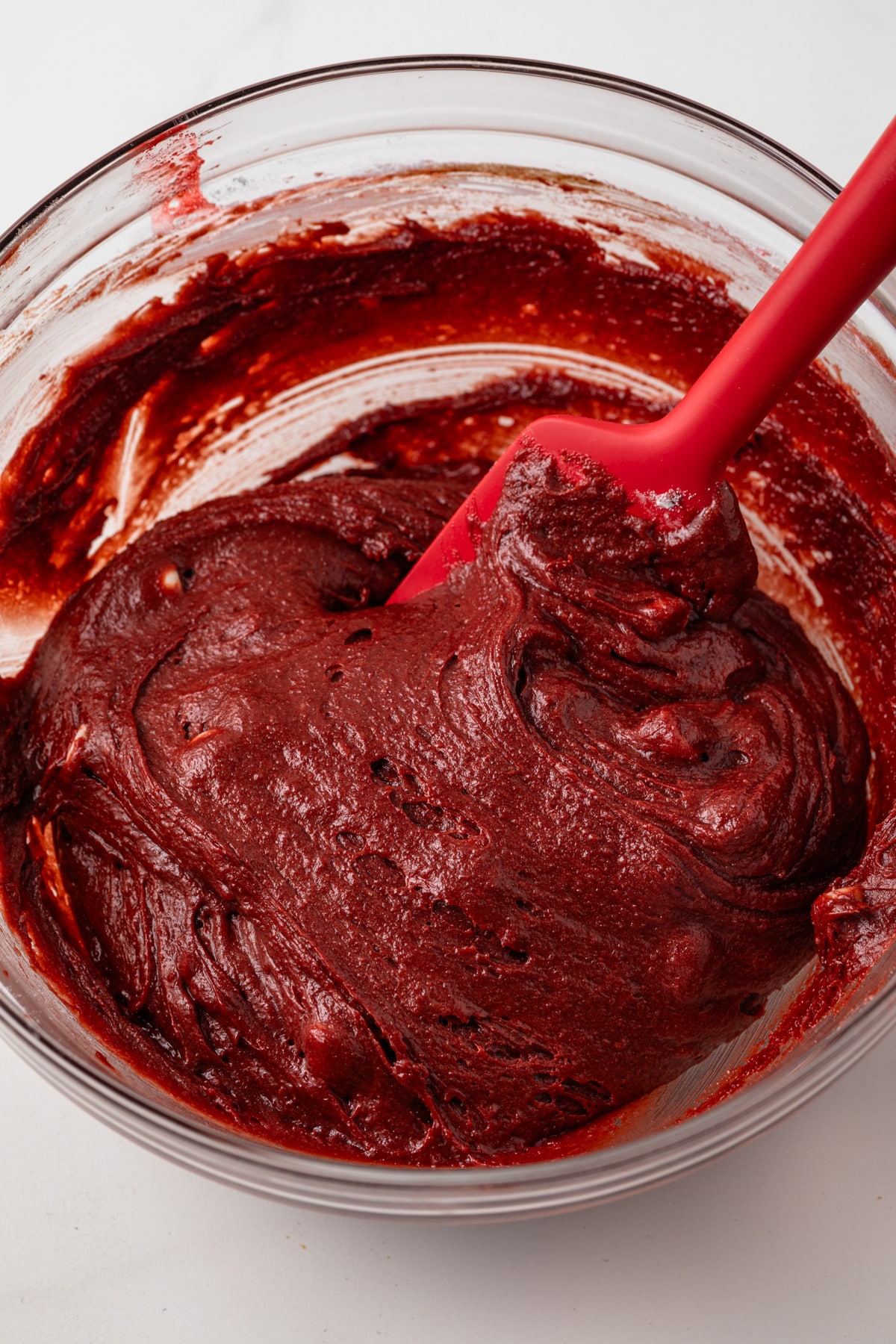 Red velvet brownie batter in glass bowl.