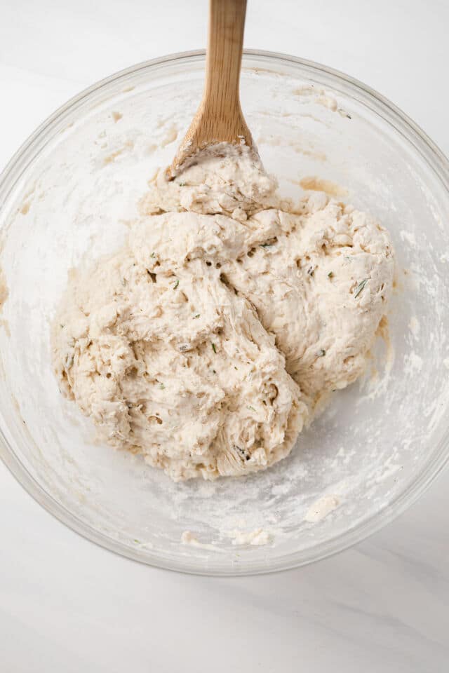 Shaggy dough mixed in a glass bowl with wooden spoon.