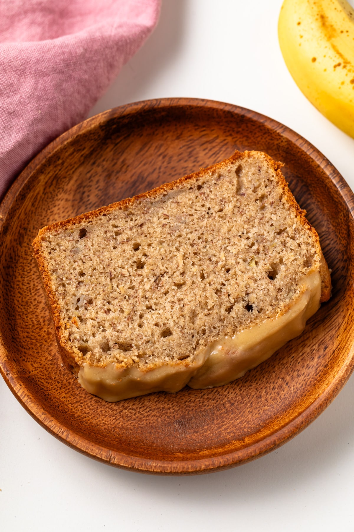 Slice of salted caramel banana bread on wooden plate.