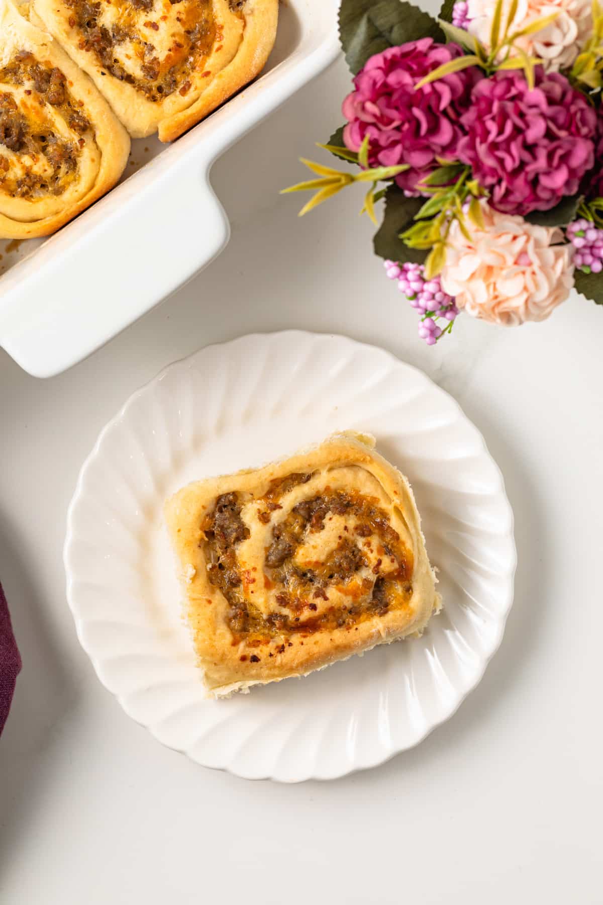 Overhead of sausage and cheese breakfast roll on plate.