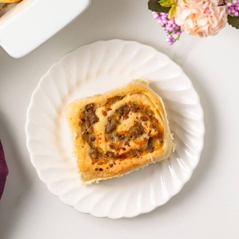 Overhead of sausage and cheese breakfast roll on plate.
