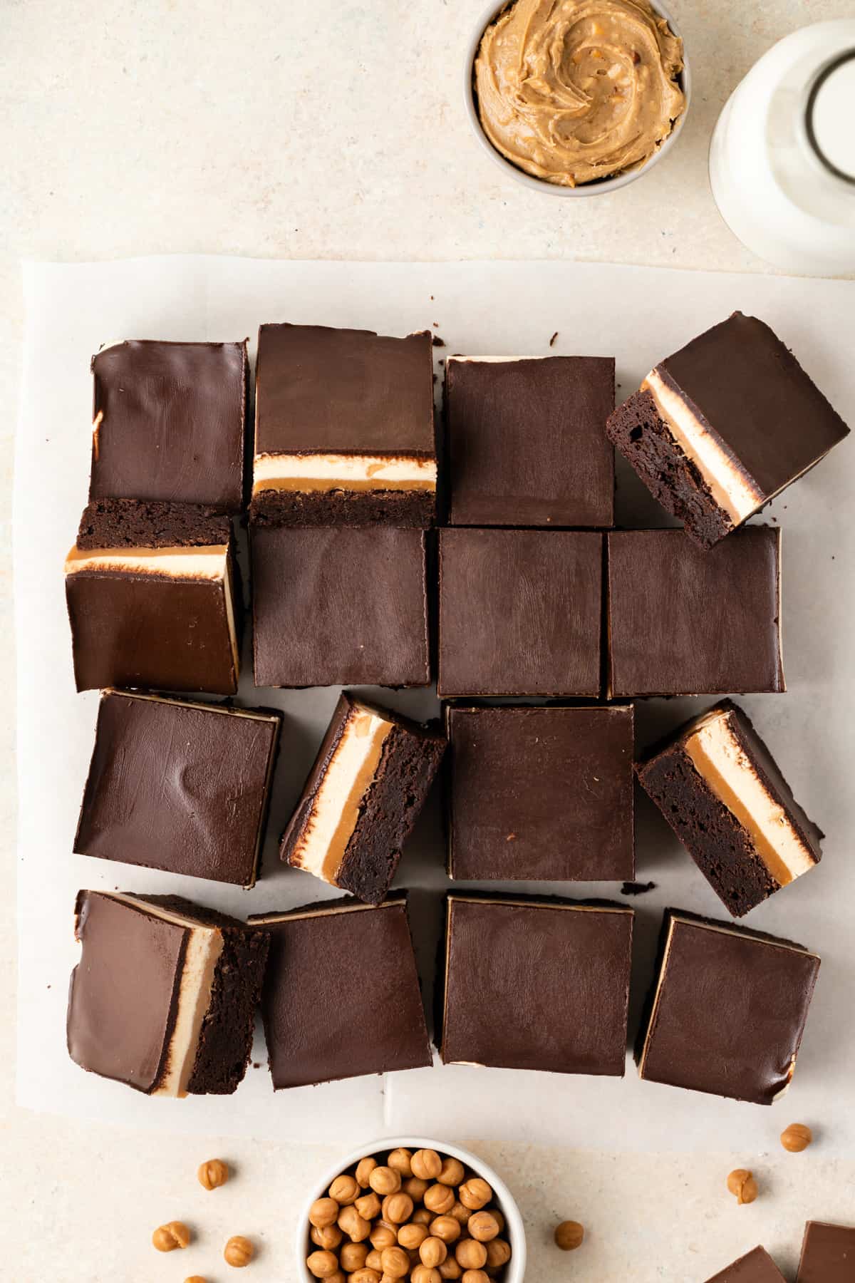 An extreme close up view of a fudgy chocolate brownie with layers of gooey caramel, chewy nougat, and chocolate ganache over the top.