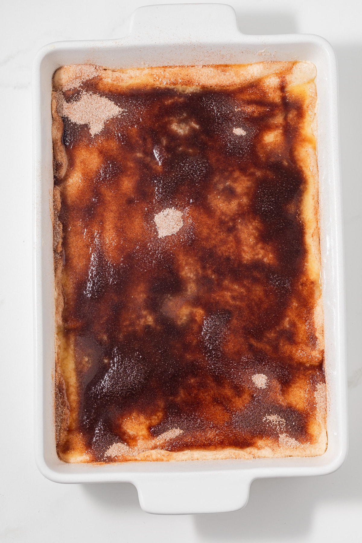 Unbaked sopapilla cheesecake in white baking dish.
