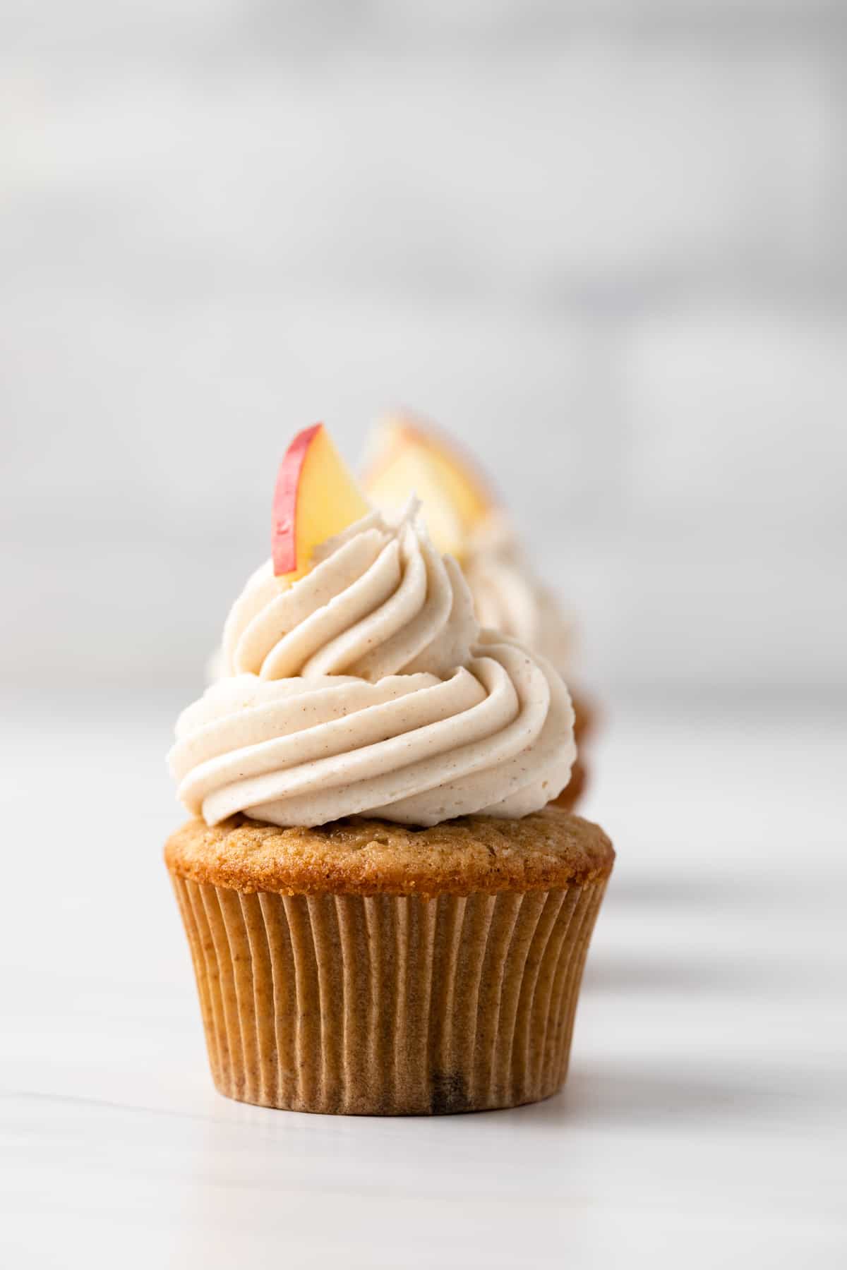 An apple spice cupcake with buttercream frosting and an apple garnish