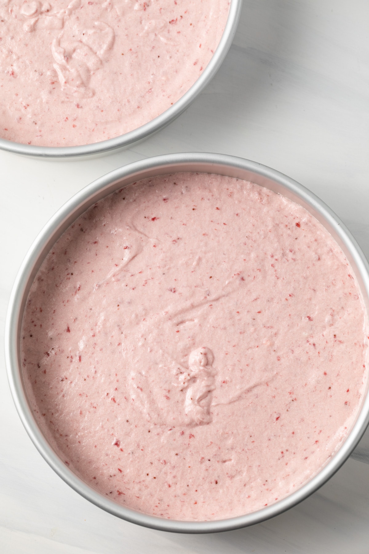 Strawberry cake batter in round baking pans.