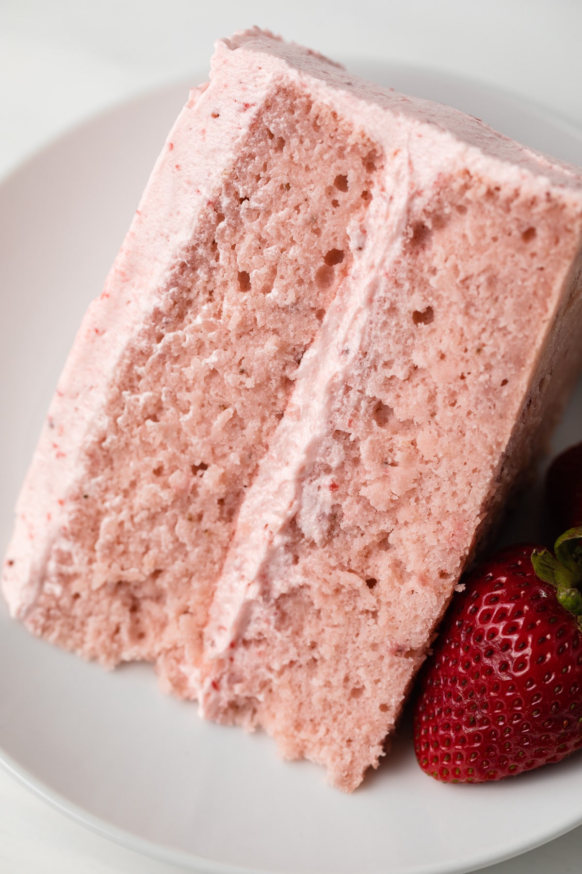 Slice of strawberry cake on a white plate.