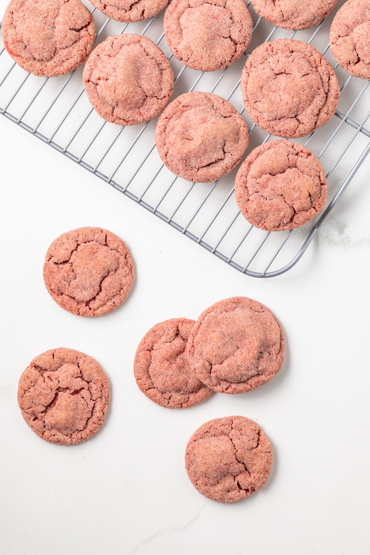 Overhead of strawberry cookies on cooling rack and counter.