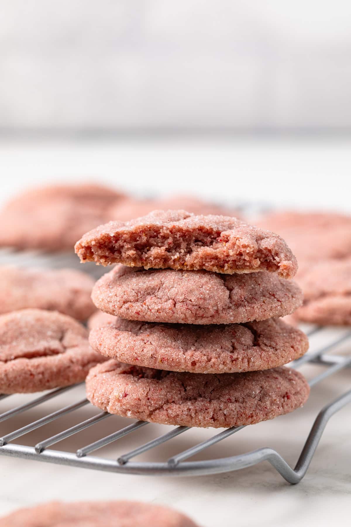 Three strawberry cookies stacked on cooling rack.