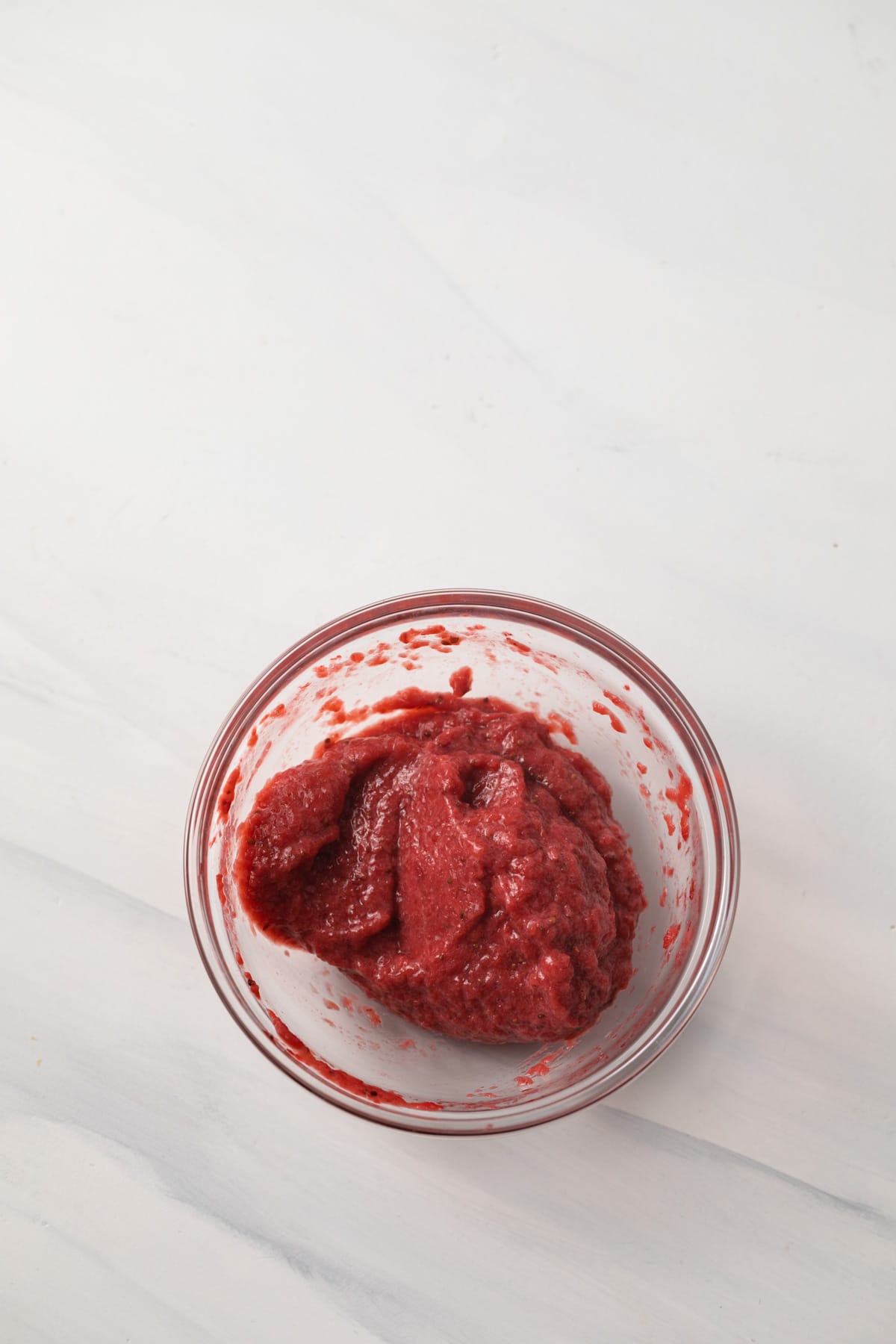 Reduced strawberry puree in glass bowl.
