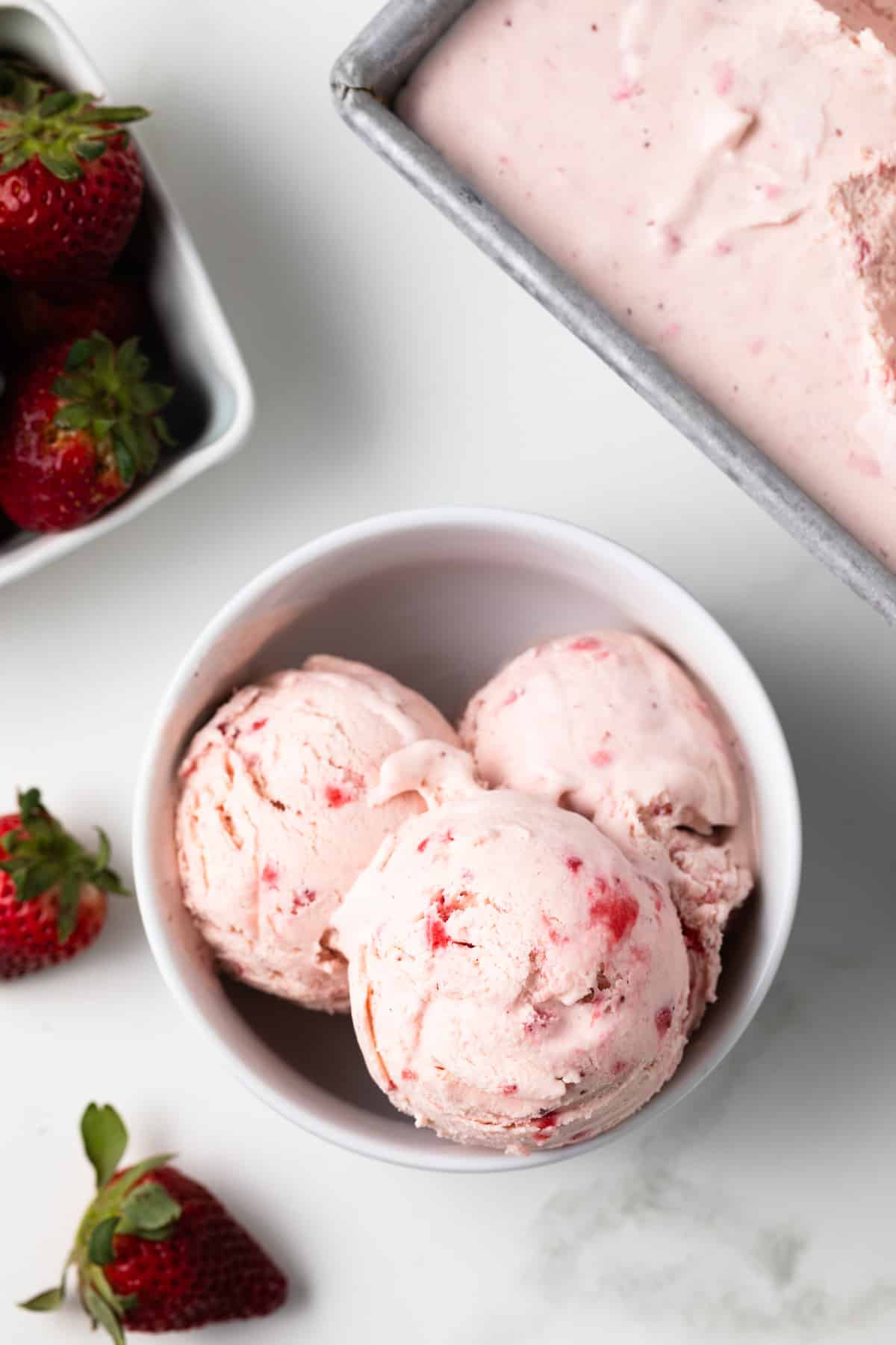Overhead of strawberry ice cream in a white bowl.