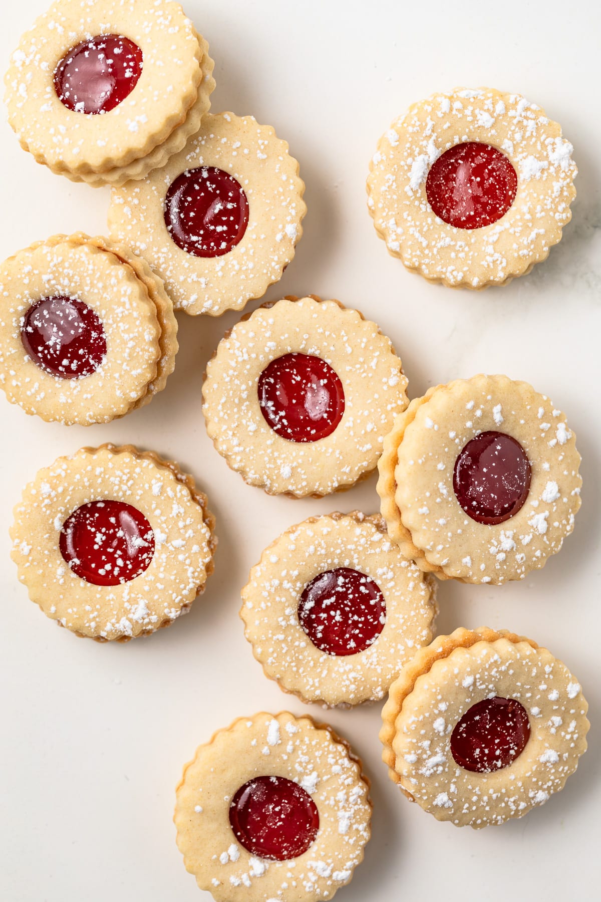 Strawberry linzer cookies spread on white background.