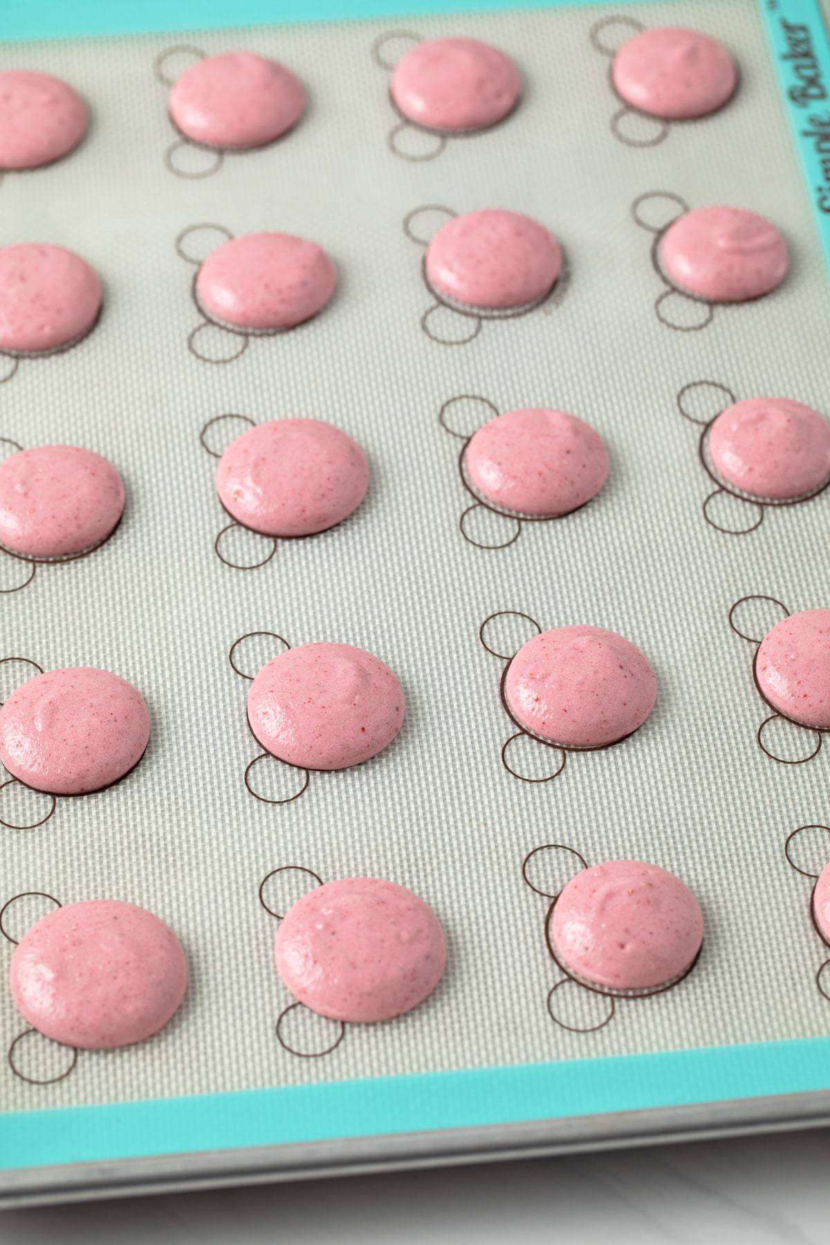 unbaked macaron shells on silicone mat