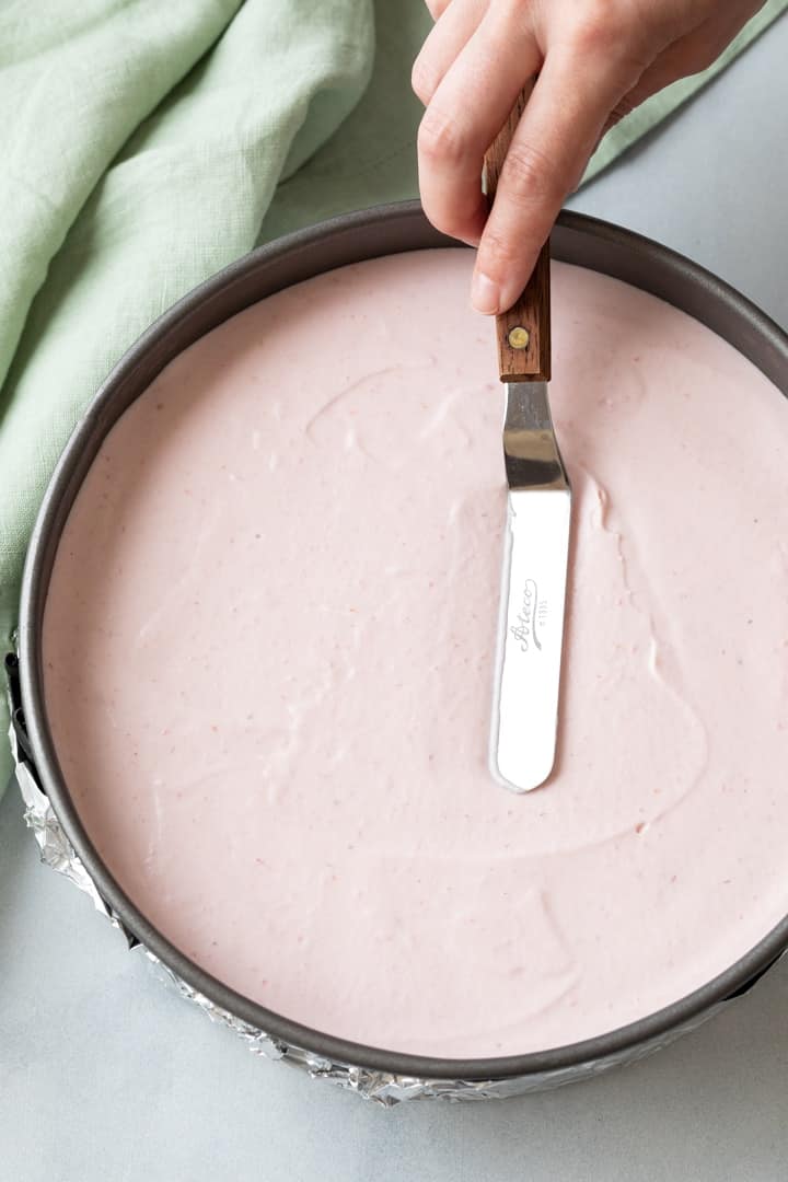strawberry mousse being smoothed over in a round pan