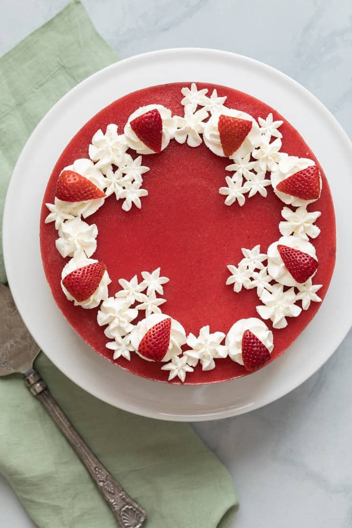 overhead of a strawberry mousse cake on a white cake stand