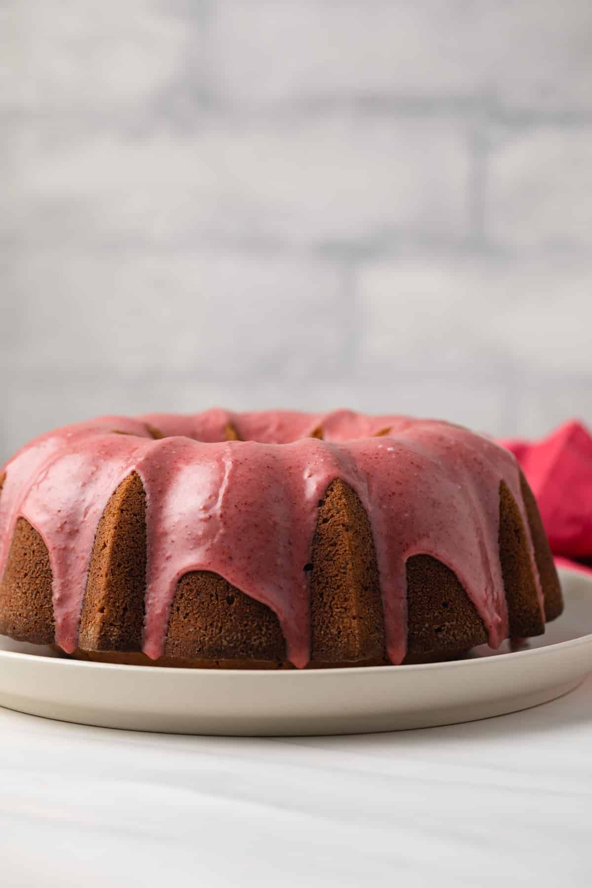 Side view of strawberry pound cake on white cake plate.