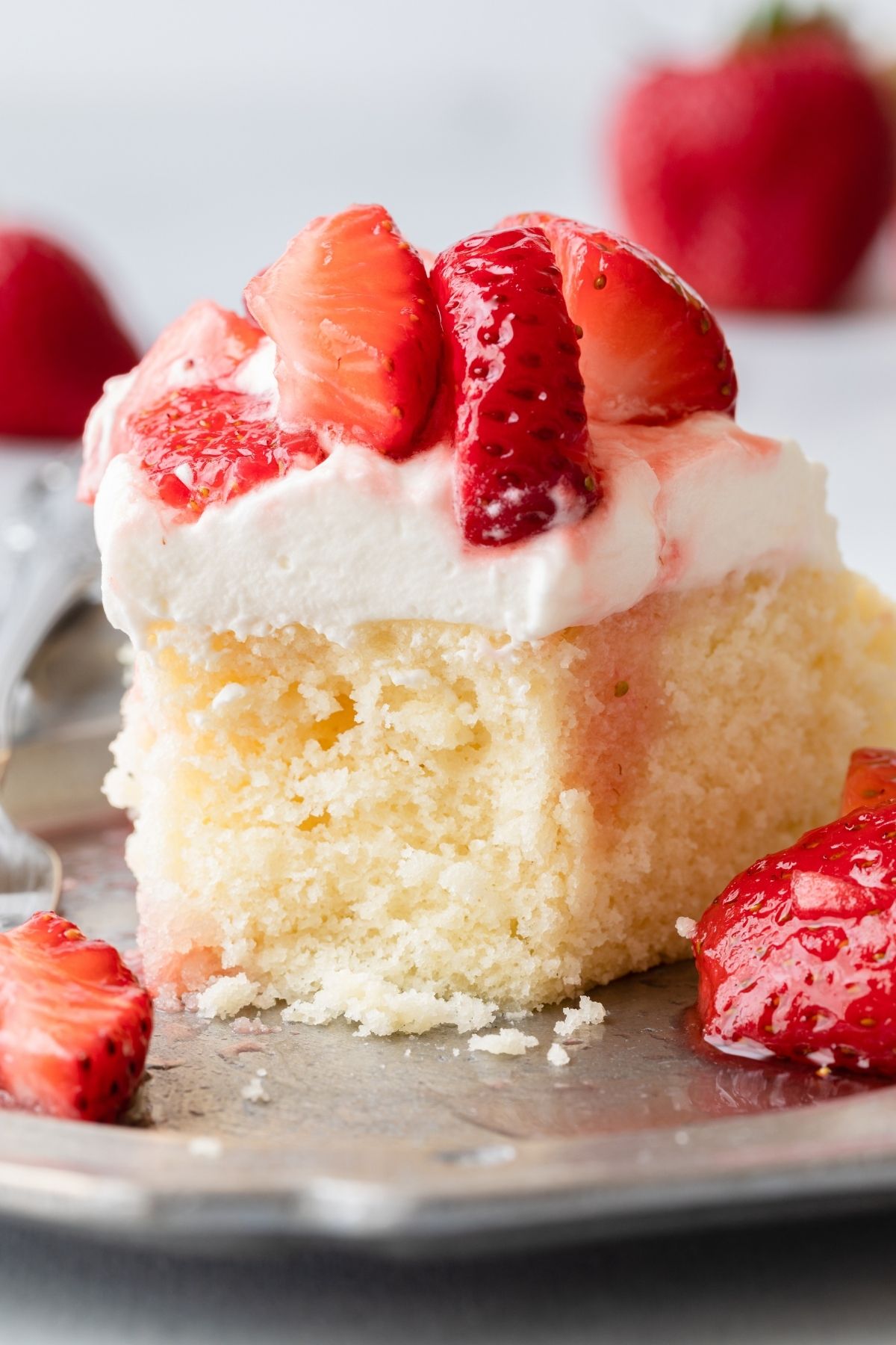 Close up of slice of strawberry shortcake cake with a bite missing.