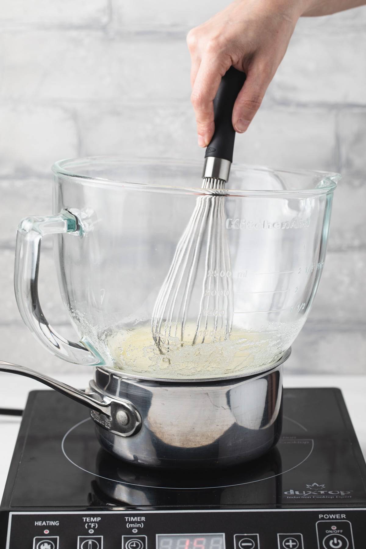 egg whites and sugar in glass bowl over pot of simmering water