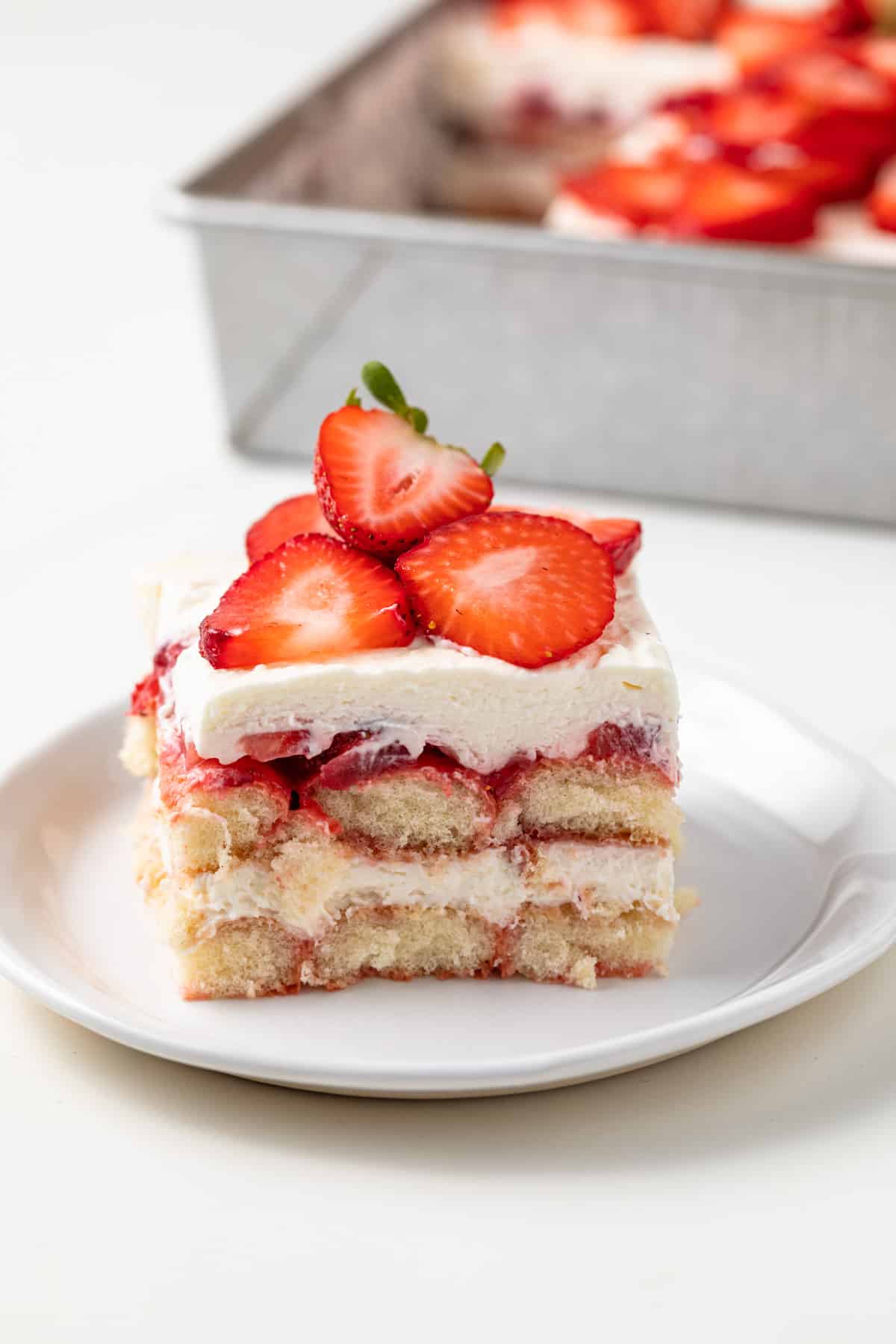 Side view of slice of strawberry tiramisu on white plate.
