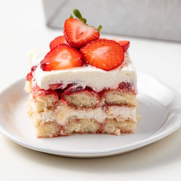 Side view of slice of strawberry tiramisu on white plate.