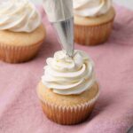 piping swiss meringue buttercream on cupcakes