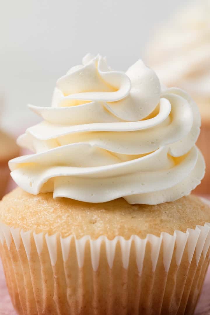 close up of swiss meringue buttercream swirled on top of cupcake
