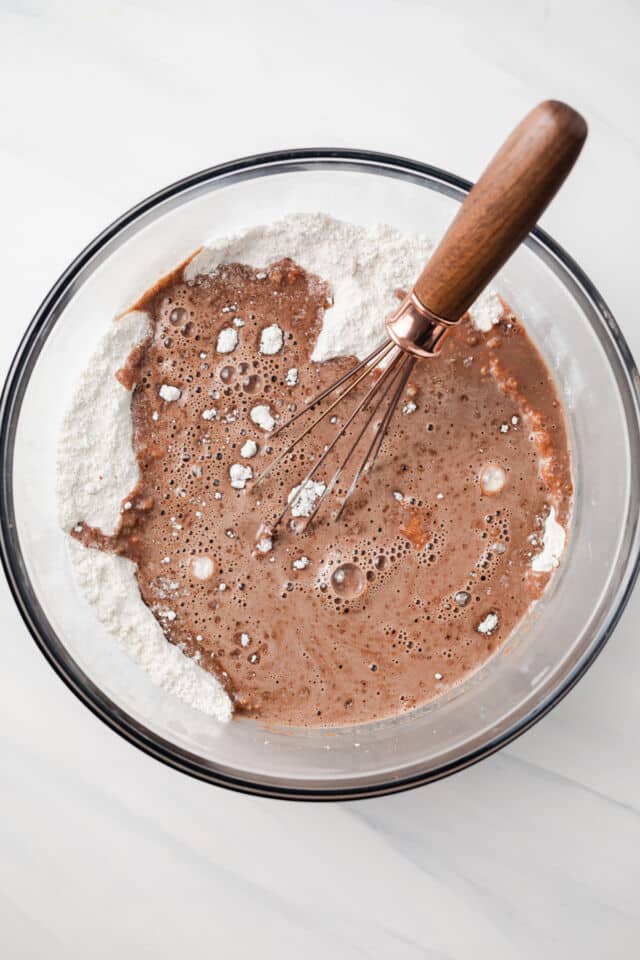 Wet and dry ingredients combined in glass bowl.