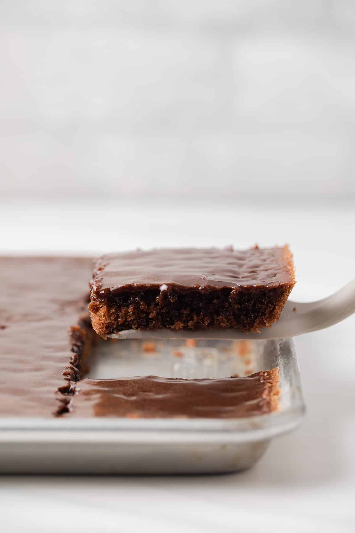 Slice of texas sheet cake being removed from pan.