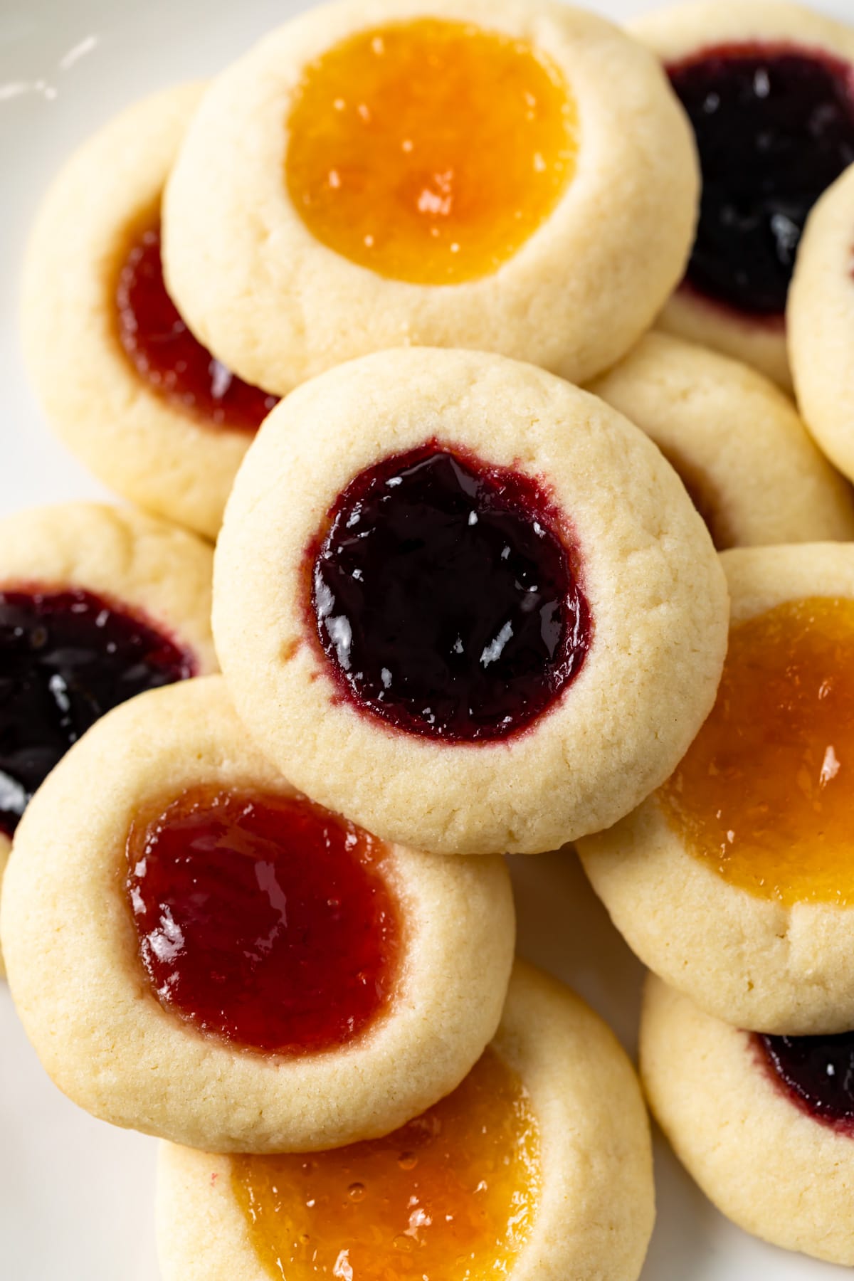 close up of thumbprint cookies stacked on white plate