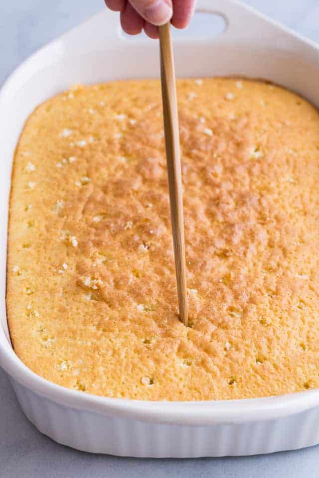 sponge cake being poked with a wooden skewer