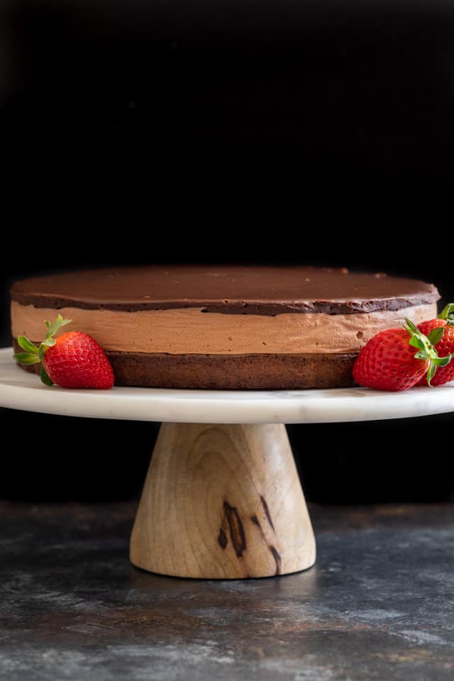 Triple Nutella mousse cake with strawberries on a cake stand.