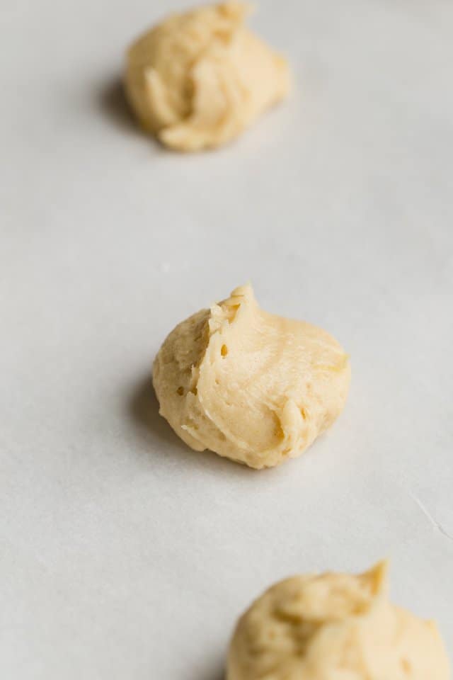 Lemon cookie dough balls on white parchment paper.