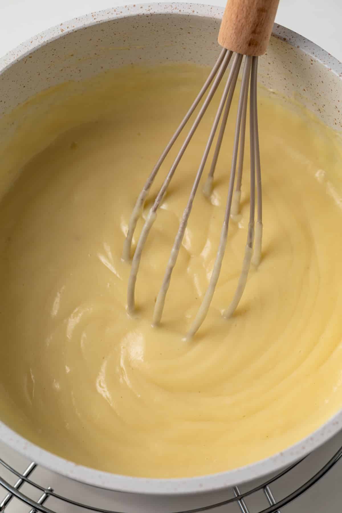 Vanilla pudding in a saucepan with whisk.