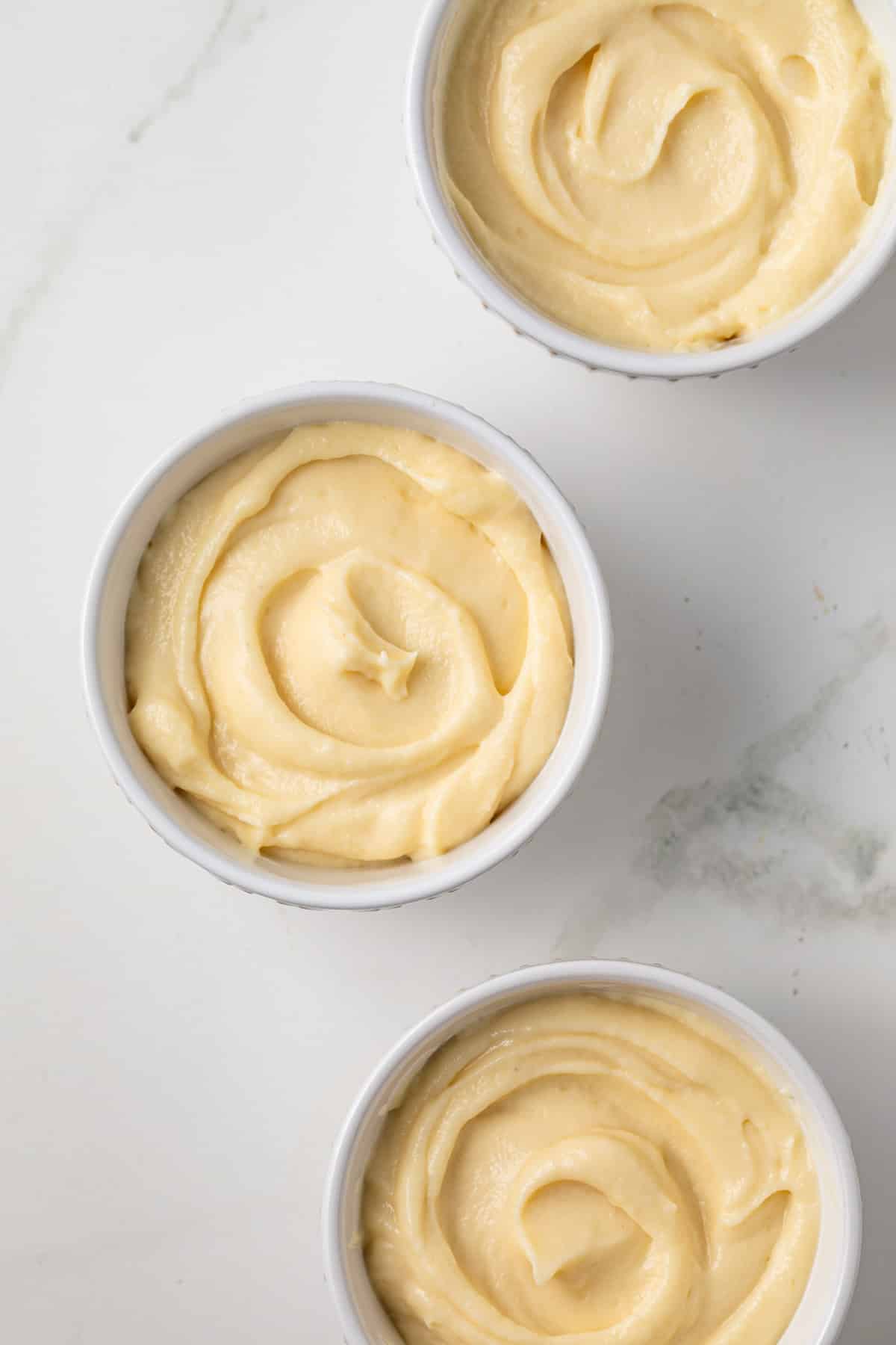 Three bowls of vanilla pudding.