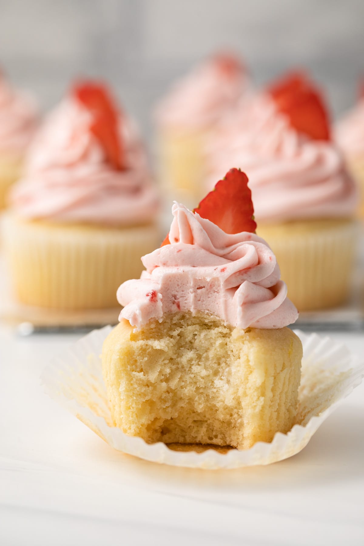Vanilla cupcake with a bite taken out.