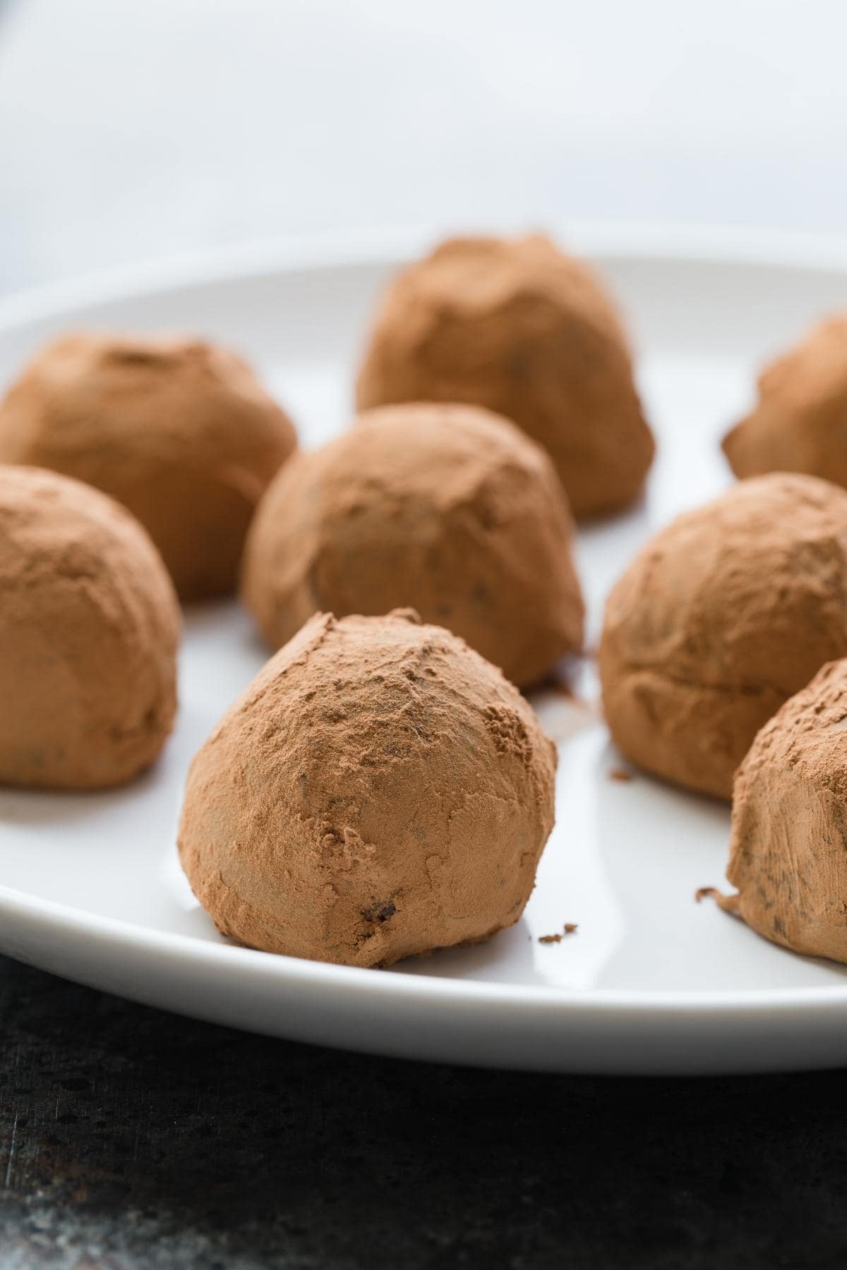 Vegan chocolate truffles neatly arranged on a white plate.